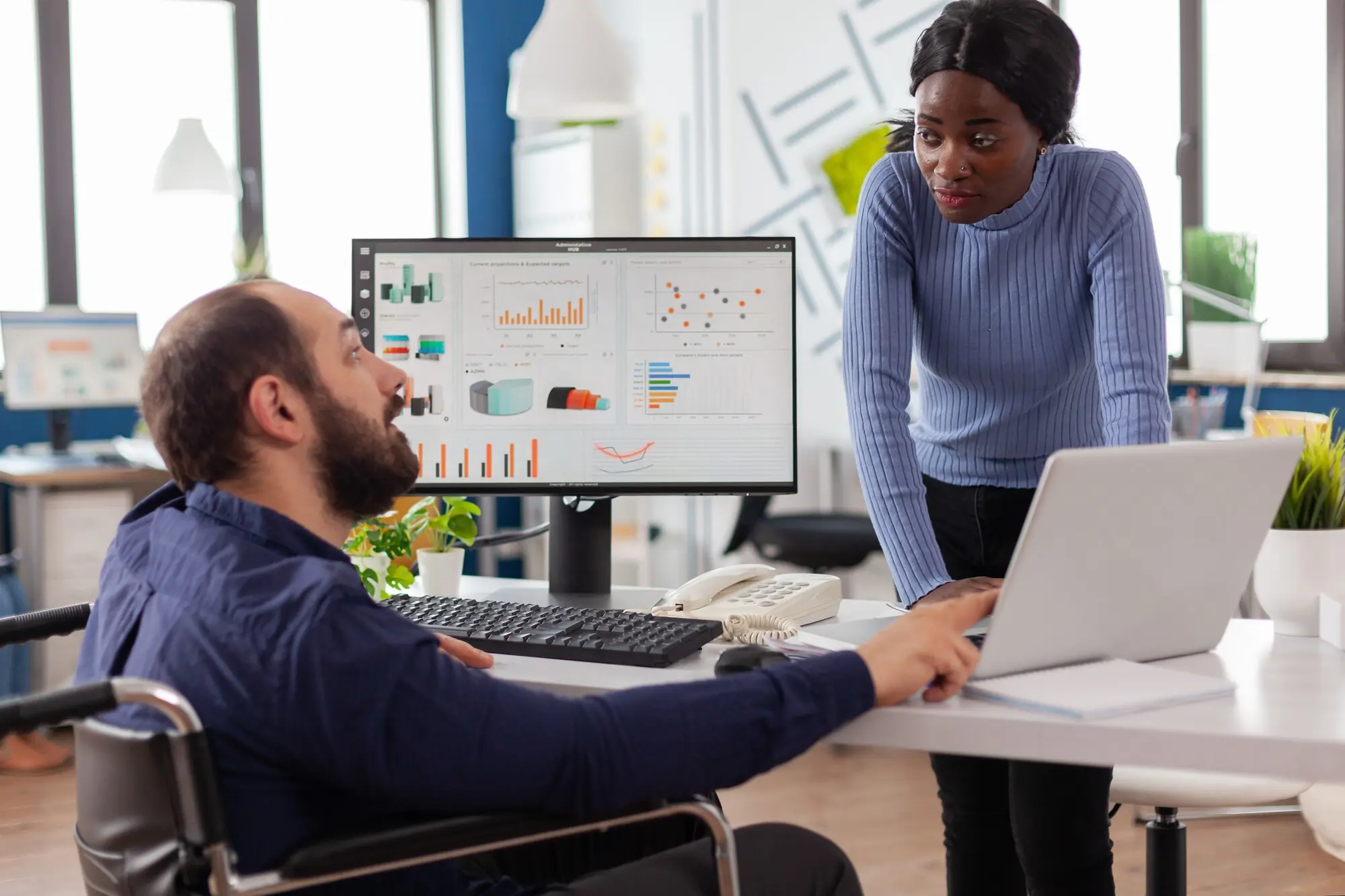 Geschäftsmann mit Behinderung und Mitarbeiter arbeiten gemeinsam an einem Finanzprojekt für ein Start-up-Unternehmen, praxisnah und nachvollziehbar.